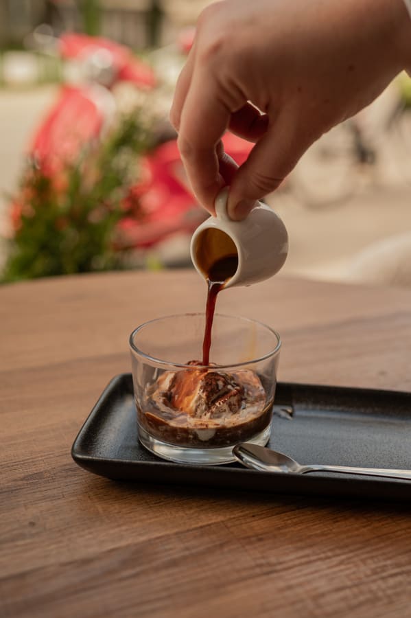 Espresso poured from a small jug over a scoop of ice cream in a glass
